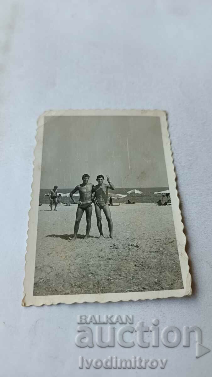 Foto Doi tineri în costume de baie pe plajă