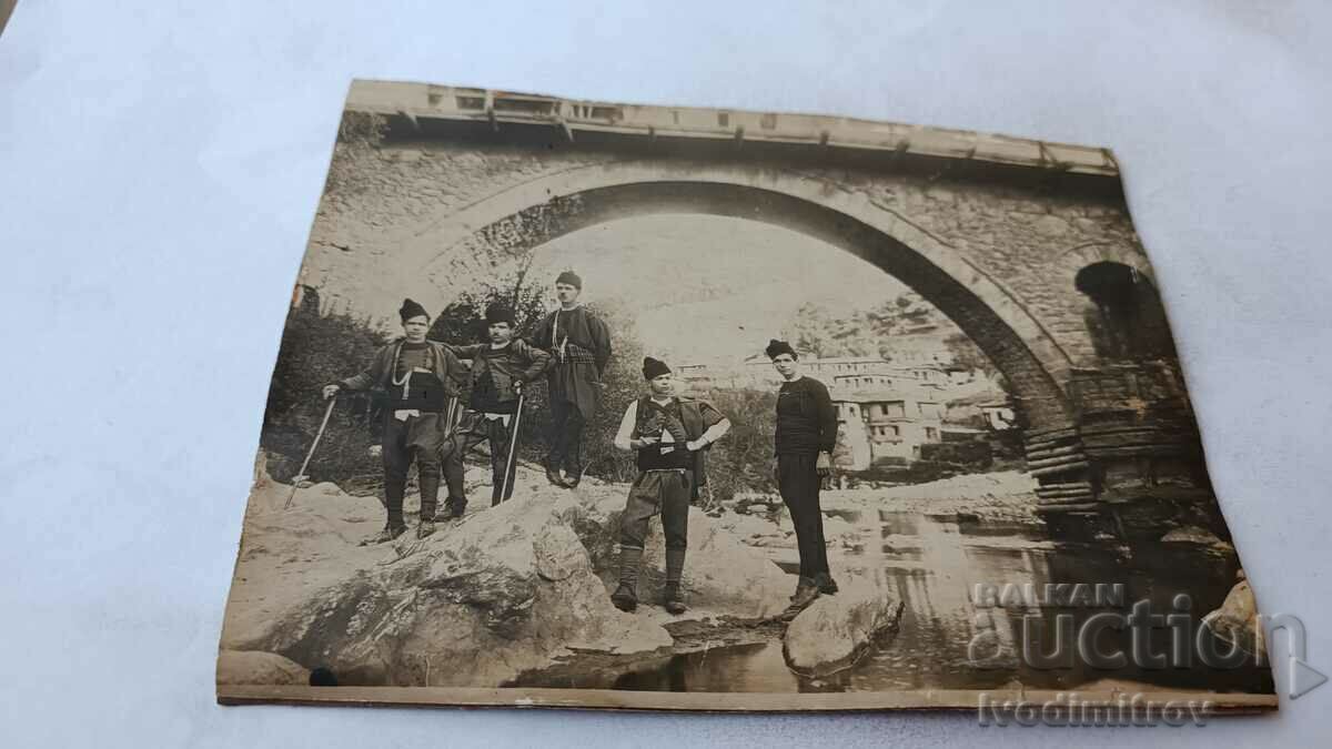 Fotografie Bărbați în haine tradiționale sub un pod de pe râul Karton