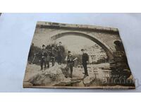 Φωτογραφία Άνδρες με παραδοσιακή ενδυμασία κάτω από μια γέφυρα στον ποταμό Karton