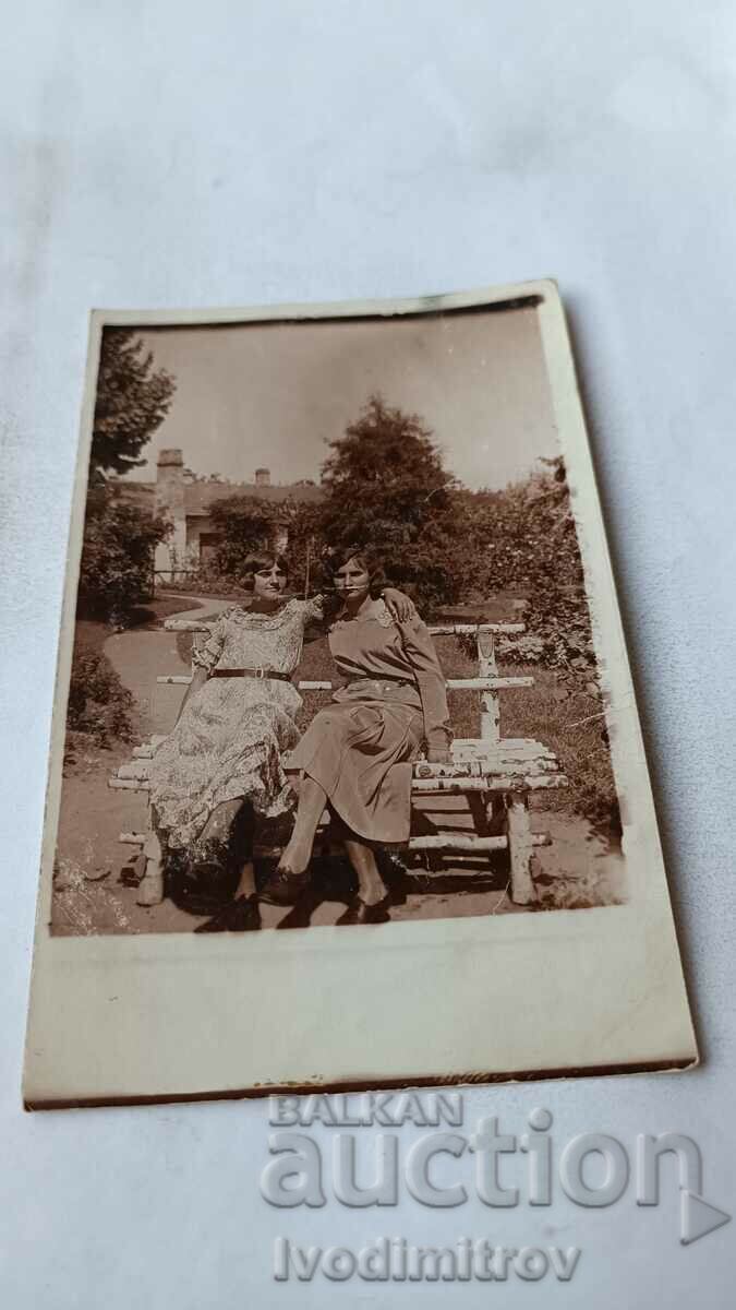 Φωτογραφία Δύο νεαρά κορίτσια που κάθονται σε έναν πάγκο σημύδας