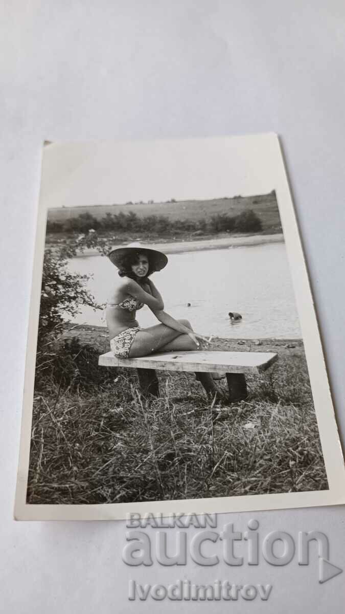 Photo Young girl in a swimsuit on a wooden bench