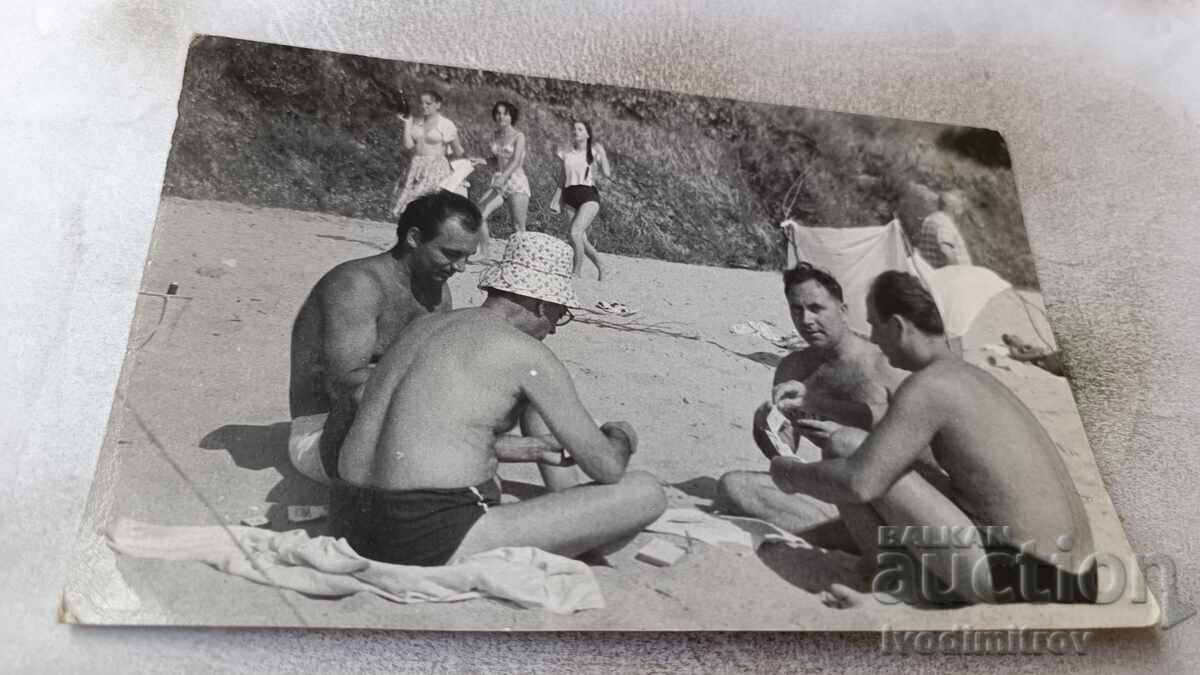 Φωτογραφία Τέσσερις άντρες που παίζουν χαρτιά στην παραλία