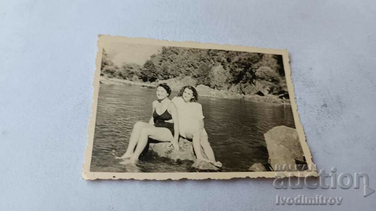 Photo Two young women sitting on a stone in the river