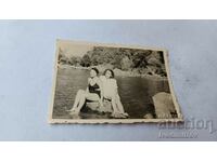 Photo Two young women sitting on a stone in the river