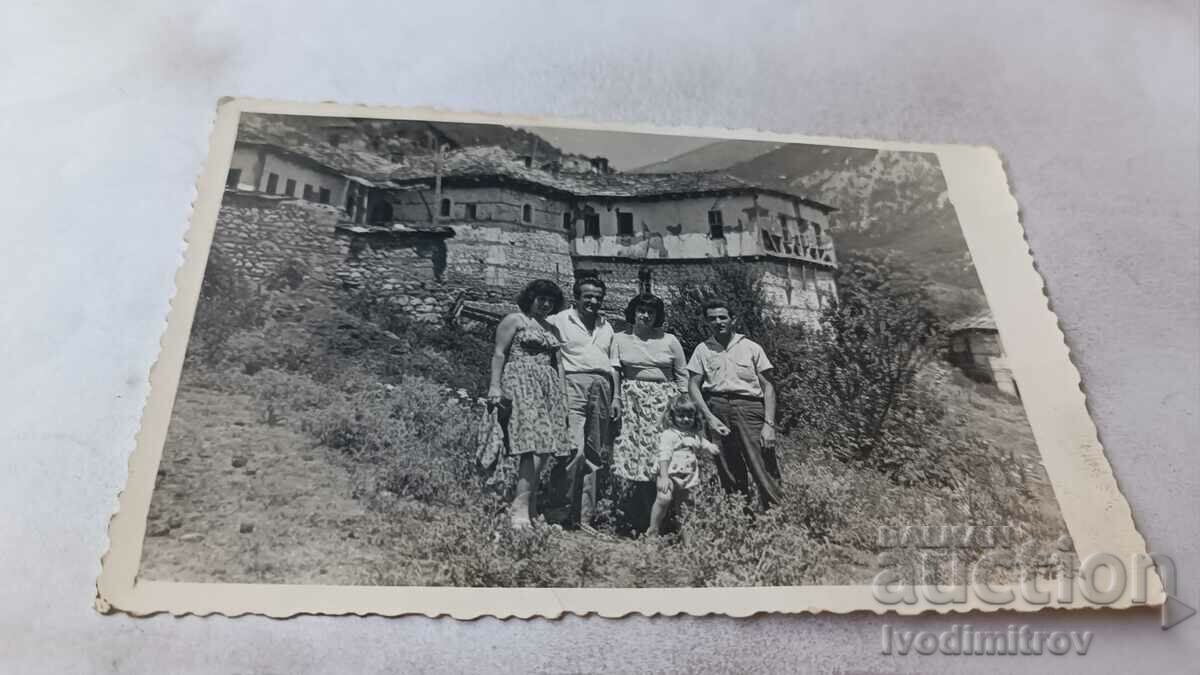 Φωτογραφία Άνδρες, γυναίκες και ένα κορίτσι μπροστά από παλιά σπίτια της Ροδόπης