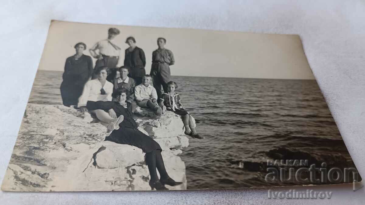 Photo Two men women and children on a cliff above the sea