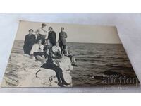 Fotografie Doi bărbați, femei și copii pe o stâncă deasupra mării