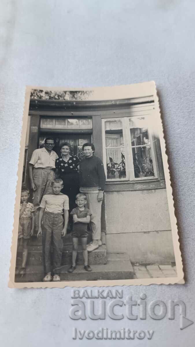 Fotografie Un bărbat, două femei și copii în pragul unei case