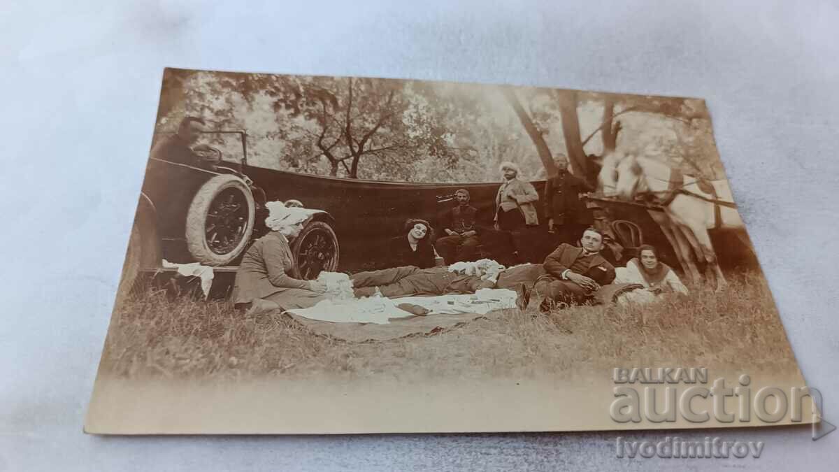 Photo Young men and women with a wagon and a car. on a picnic