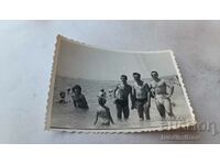 Foto Trei bărbați, o femeie și copii pe plajă