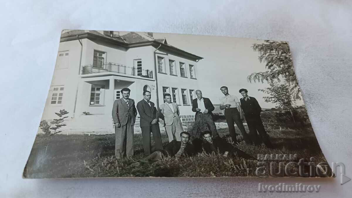 Photo Men in the grass in front of a building