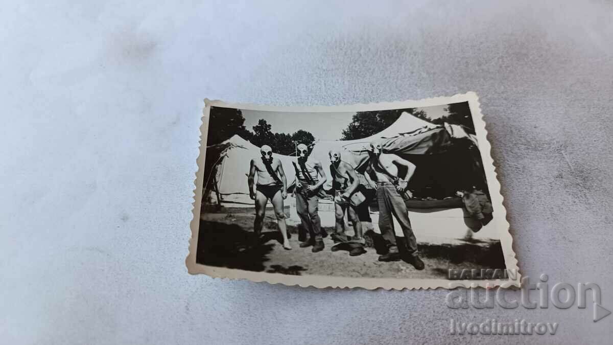 Photo Four soldiers with gas masks in front of tents