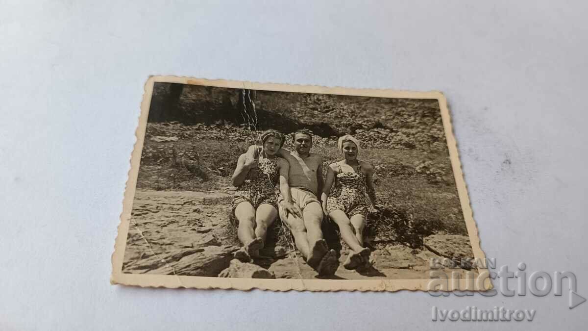 Φωτογραφία Ένας νεαρός άνδρας και δύο νεαρές γυναίκες σε βράχια δίπλα στη θάλασσα