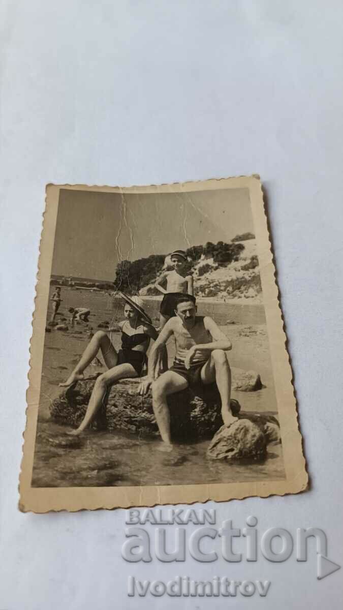 Φωτογραφία Βάρνα Άνδρας, αγόρι και κορίτσι σε μια πέτρα στην ακτή