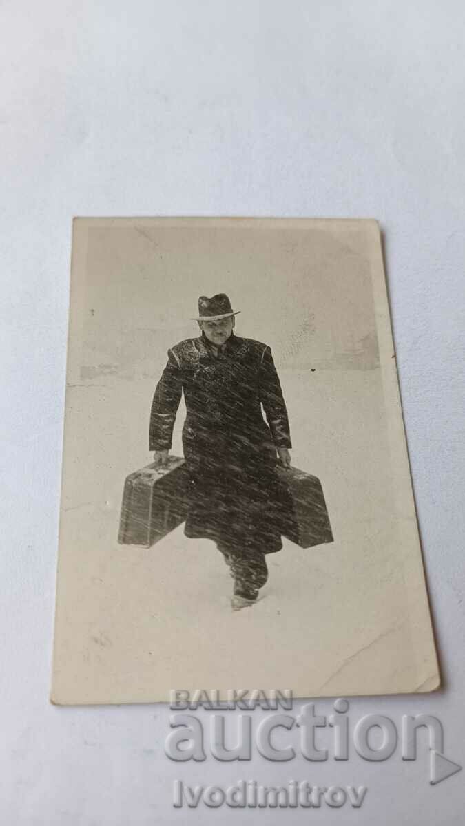 Photo Sofia A man in a winter coat with two suitcases in a blizzard