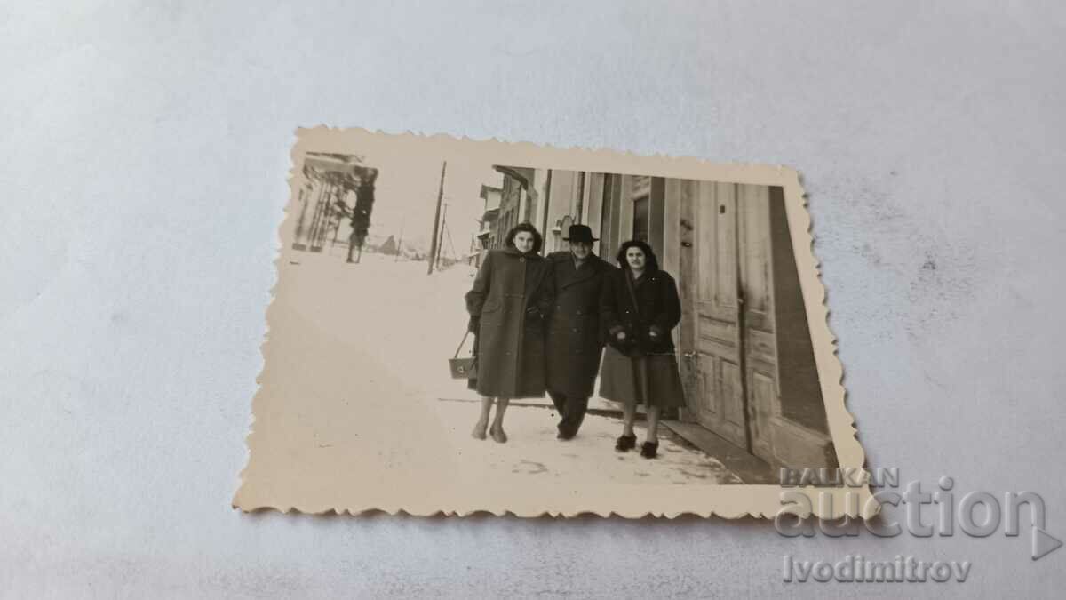 Φωτογραφία Σοφία Ένας άντρας και δύο γυναίκες με χειμωνιάτικα παλτό στο πεζοδρόμιο