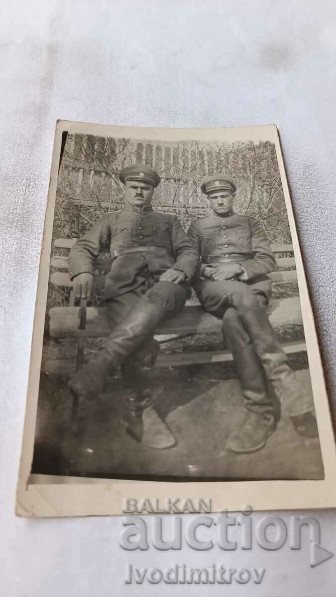 Φωτογραφία Δύο στρατιώτες που κάθονται σε έναν ξύλινο πάγκο