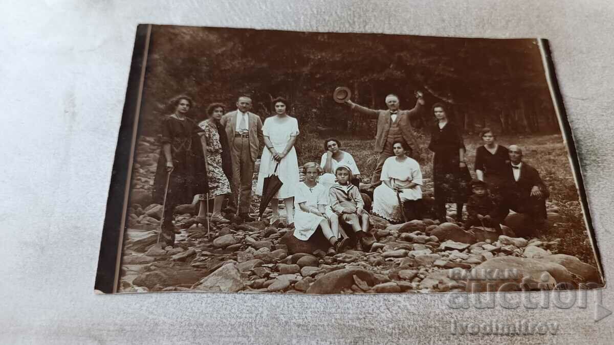Снимка Мъже жени и деца покрай поточе в планината