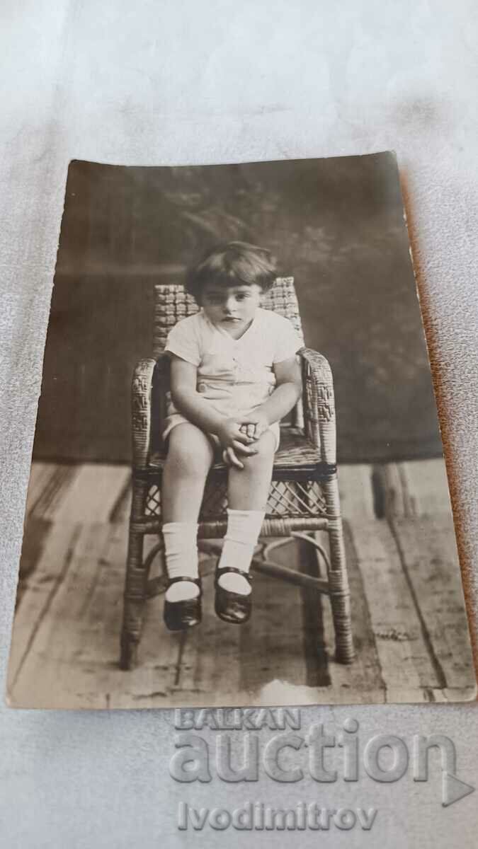 Φωτογραφία Ένα μικρό κορίτσι που κάθεται σε μια ψάθινη καρέκλα
