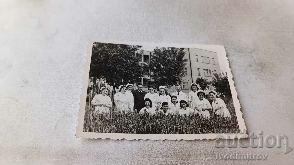 Photo Man and women in white aprons in the grass