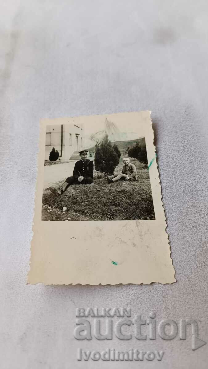 Αξιωματικοί φωτογραφιών και ένα αγόρι που κάθεται στο γρασίδι