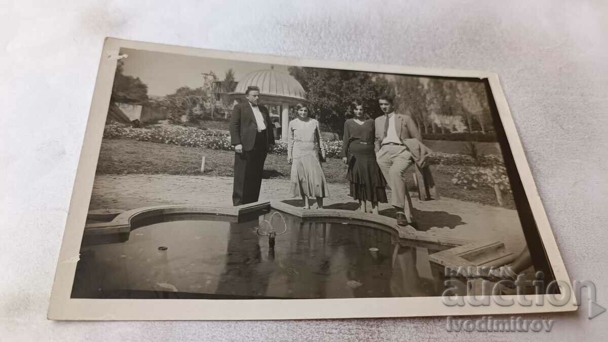 Photo Two men and two young women by a fountain in the park