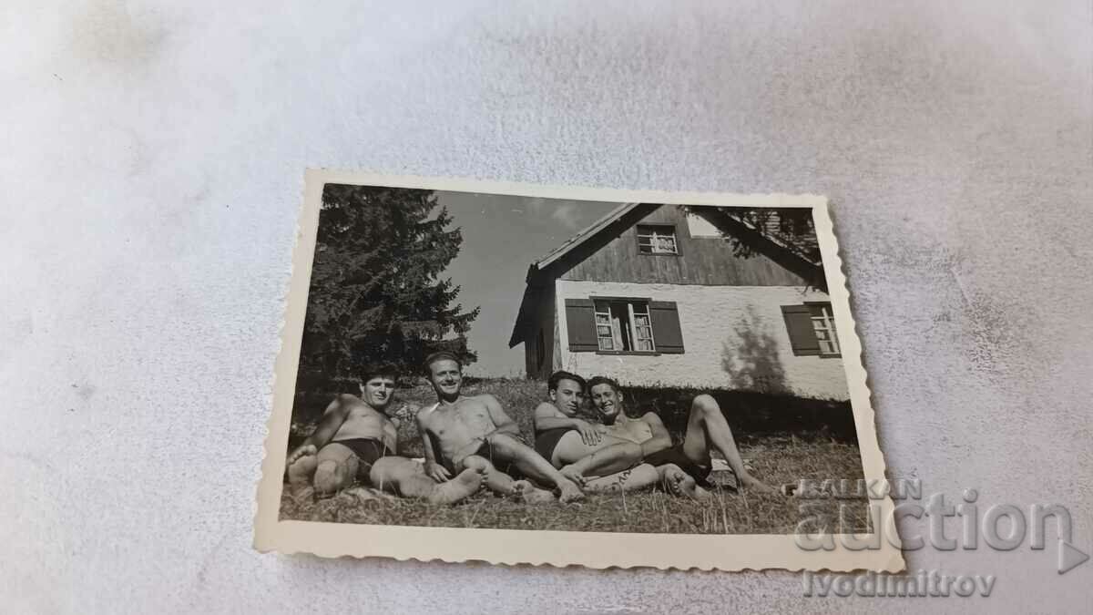 Photo Four young men in swimsuits in front of a mountain hut
