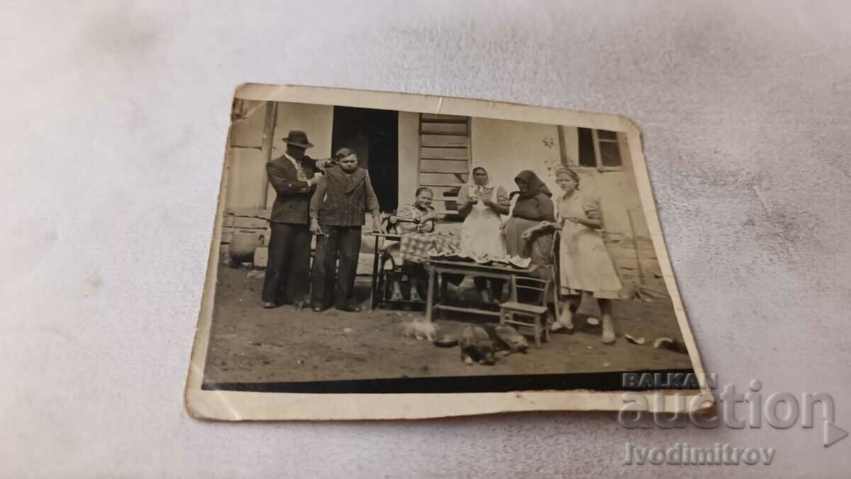Φωτογραφία Άνδρες γυναίκες και παιδιά που τρώνε καρπούζι στην αυλή του σπιτιού τους