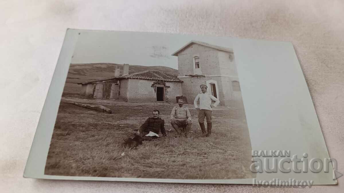 Photo Three officers on a meadow in front of an old building
