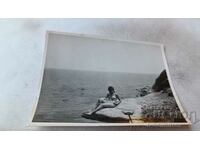 Fotografie Tânără în costum de baie pe o stâncă pe malul mării
