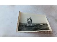 Foto Trei tineri în costume de baie pe o stâncă în mare