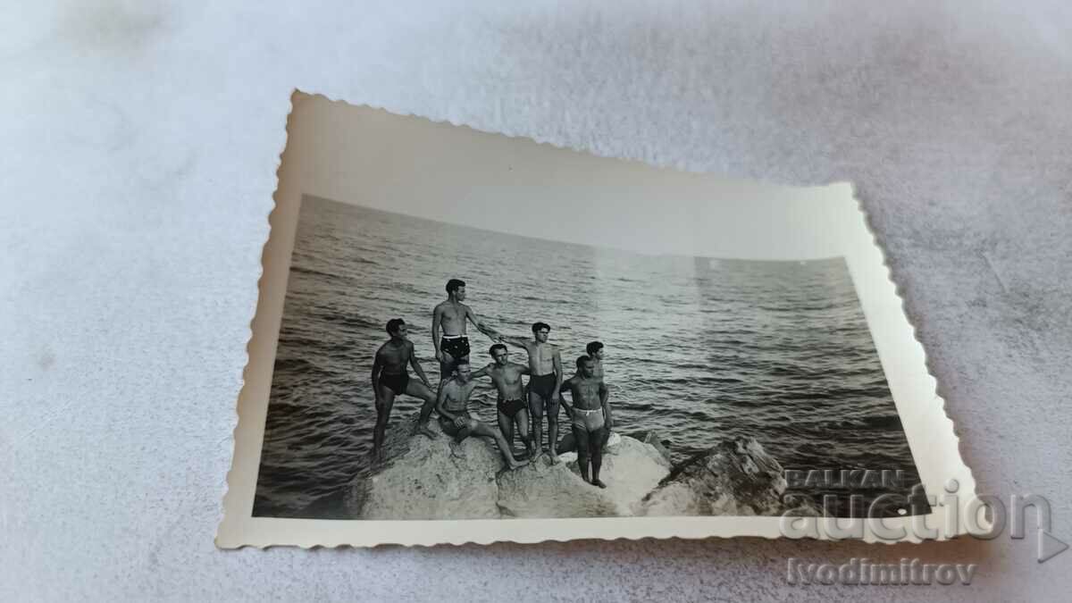 Photo Young men in swimsuits on a rock in the sea