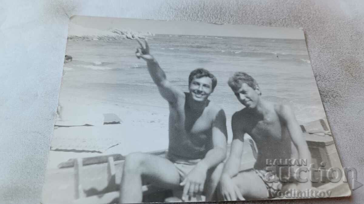 Снимка Двама млади маже по бански в дървена лодка