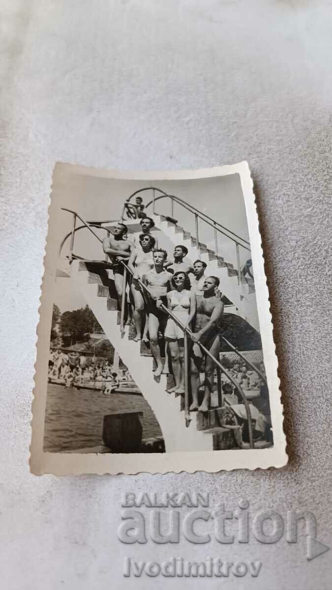 Photo Men and young woman on the ladder of a swimming pool