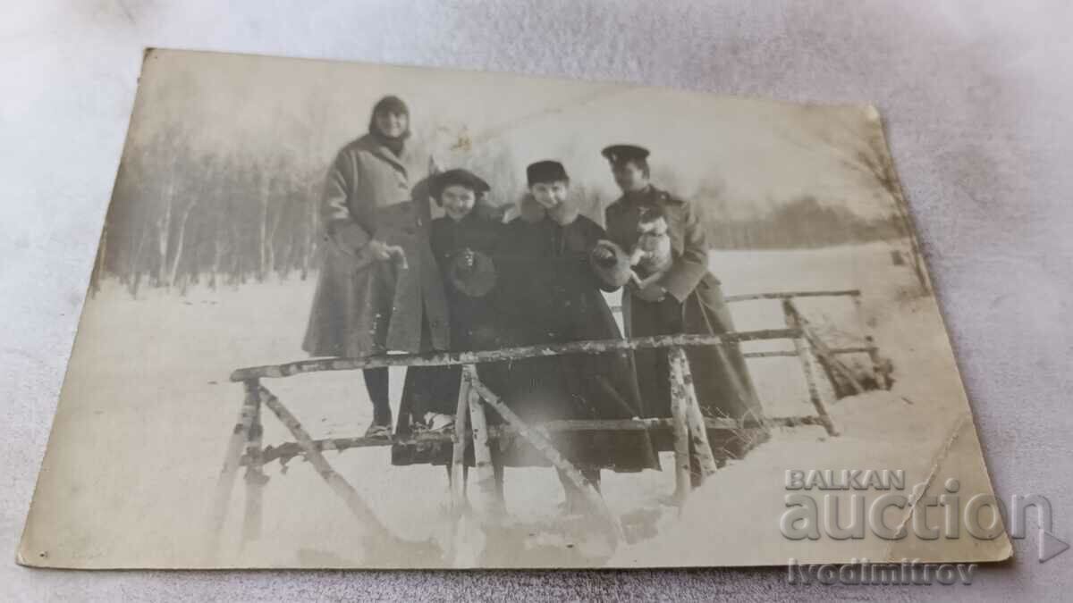 Mrs. Officer with a puppy and young women on a birch bridge in winter