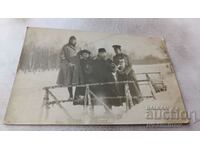Mrs. Officer with a puppy and young women on a birch bridge in winter
