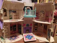 A white dollhouse with purple roofs