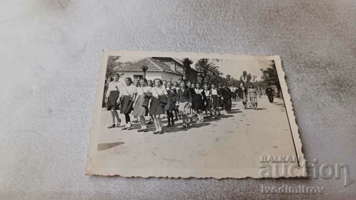 Photo Pupils in a procession along the street of the village