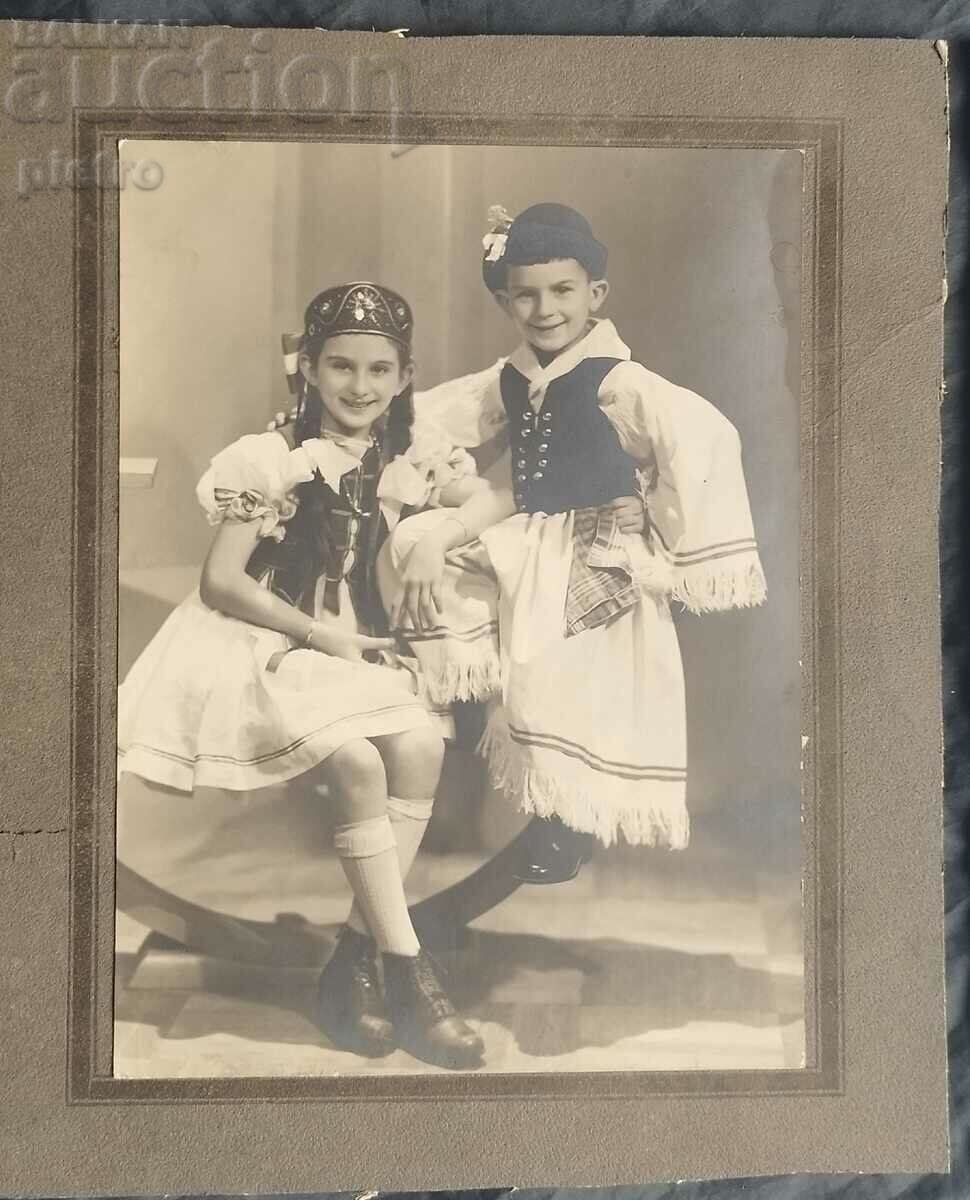 Old photo, cardboard of boy and girl in folk folklore...