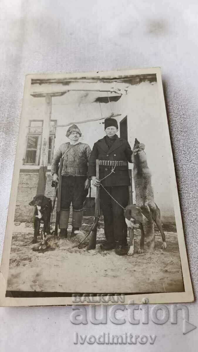 Foto Doi vânători cu doi câini de vânătoare și o vulpe trofeu