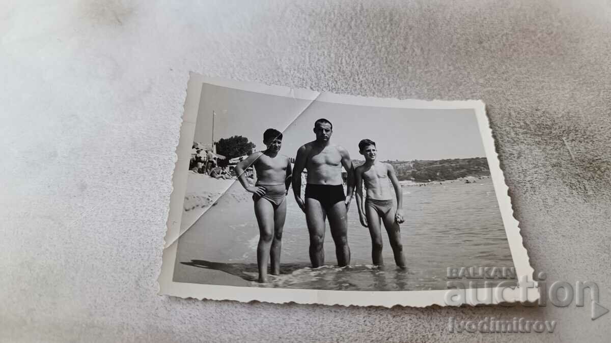 Photo A man and two boys on the beach