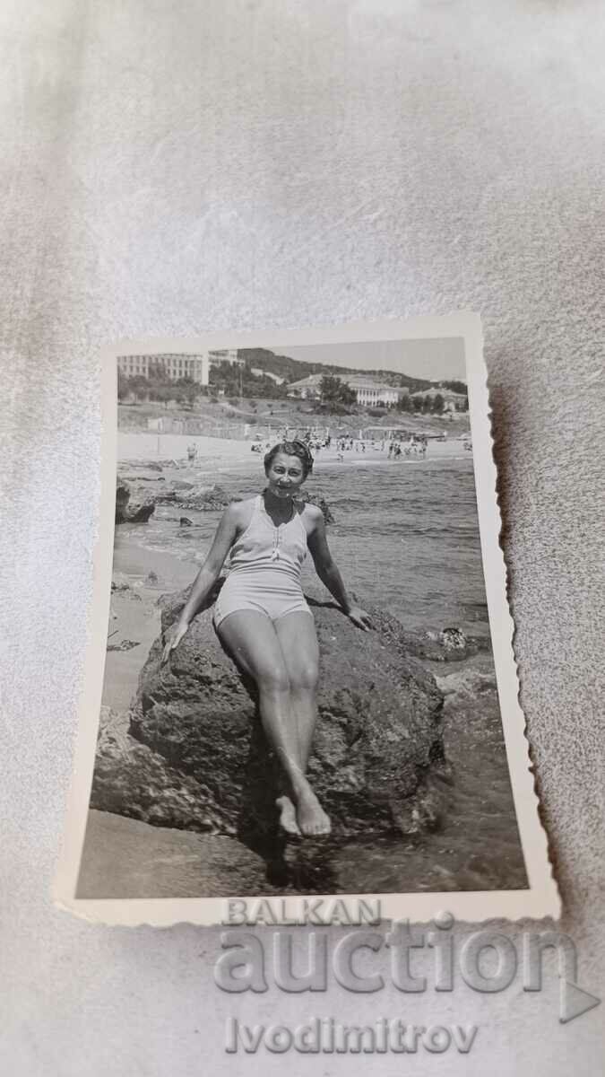Снимка Жена седнала на скала на брега на морето