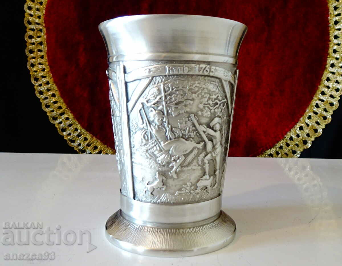 A pewter cup with three romantic paintings.