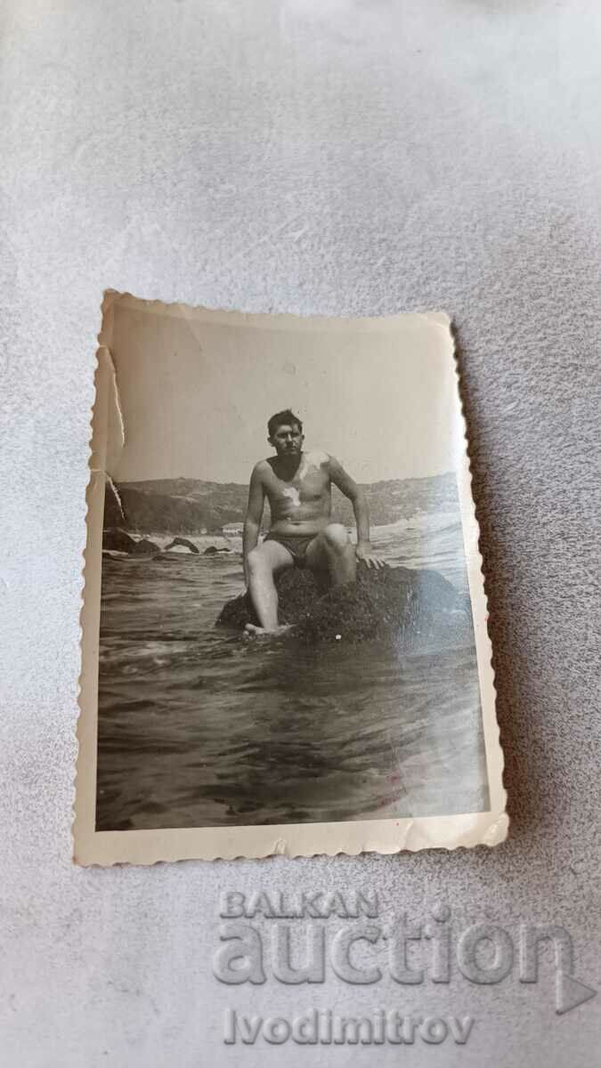 Φωτογραφία Άνθρωπος που κάθεται σε έναν βράχο στη θάλασσα