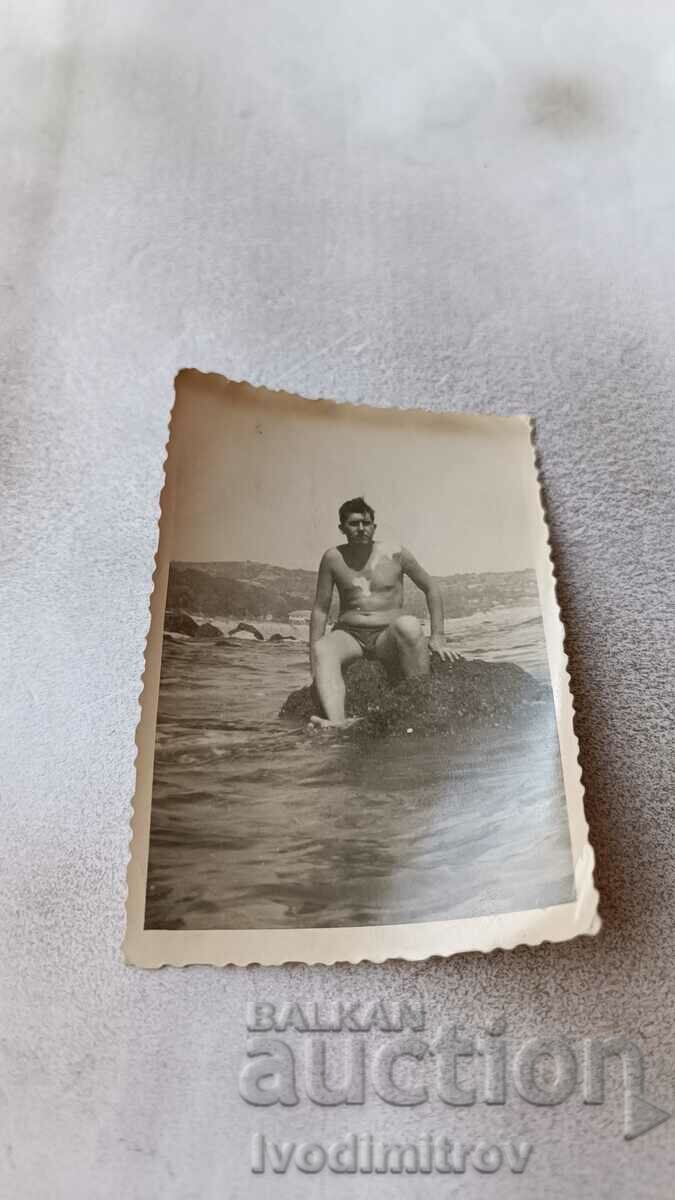 Снимка Мъж седнал на скала в морето