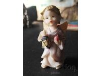 Retro figurine of a standing angel with a lamp in his hand.