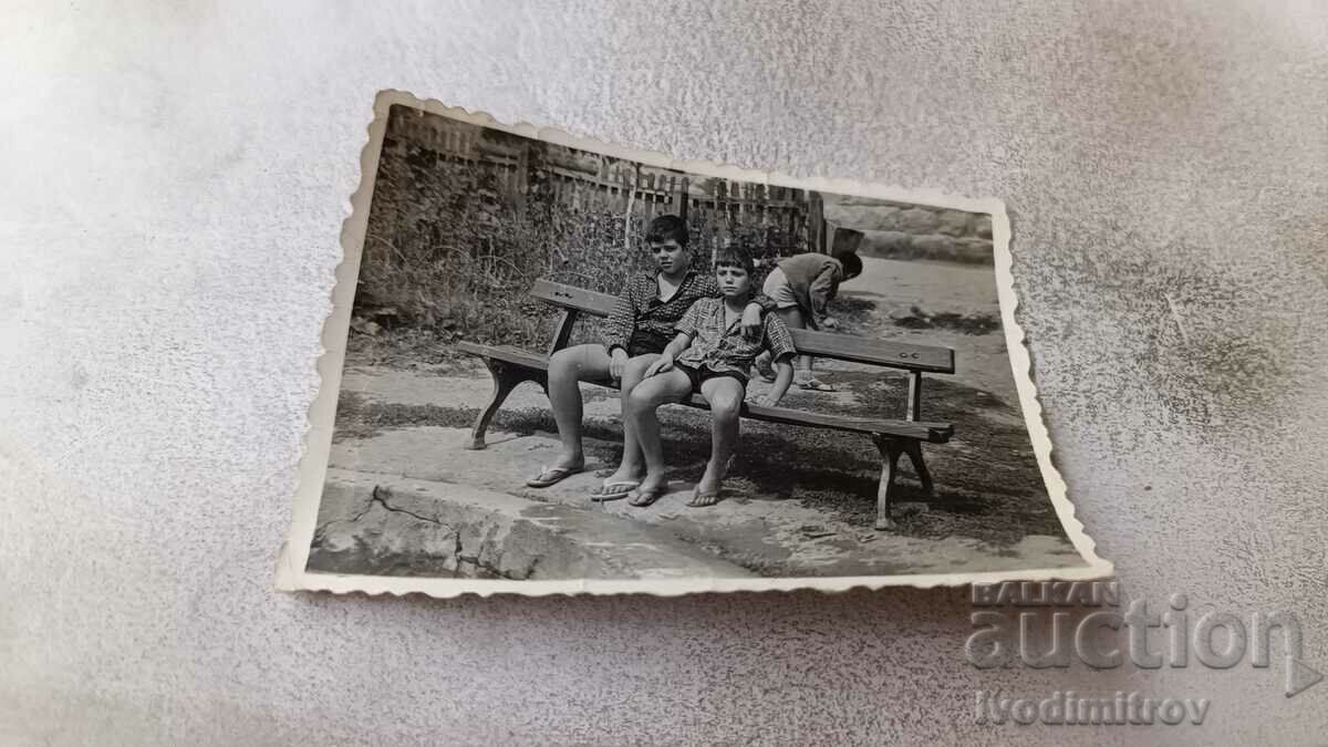 Φωτογραφία Δύο αγόρια με σορτς που κάθονται σε έναν πάγκο