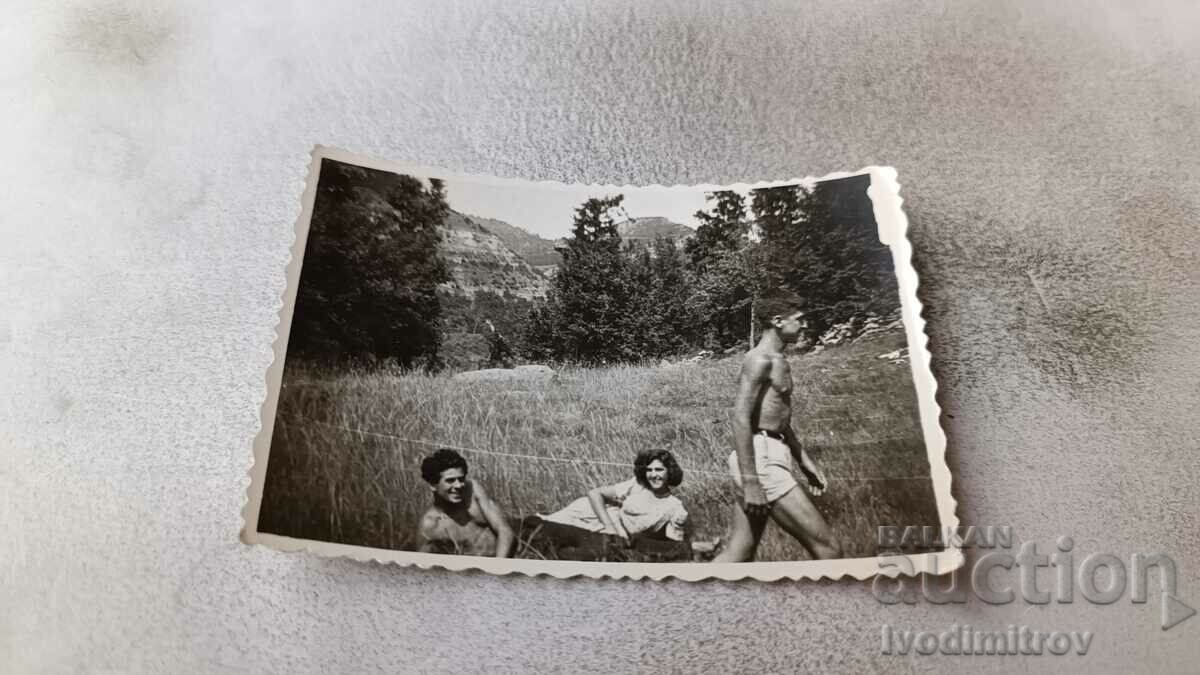 Снимка Двама младежи голи до кръста и девойка на тревата