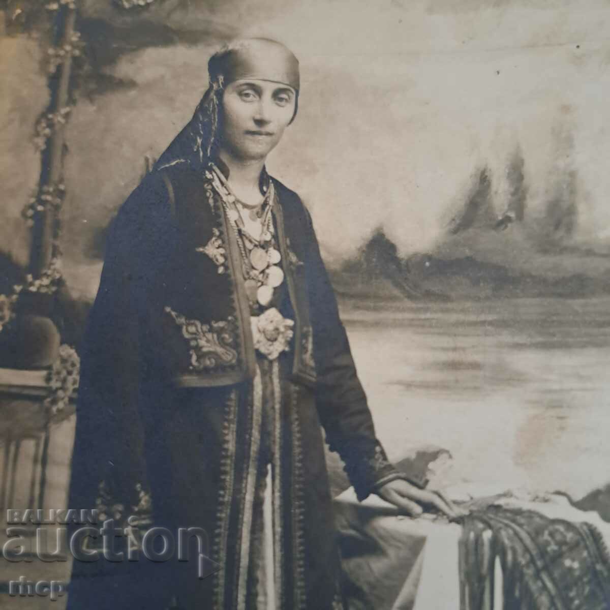 Μια γυναίκα με κοστούμι pendari κοιτάζει μια παλιά φωτογραφία