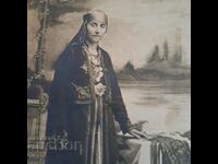 Μια γυναίκα με κοστούμι pendari κοιτάζει μια παλιά φωτογραφία